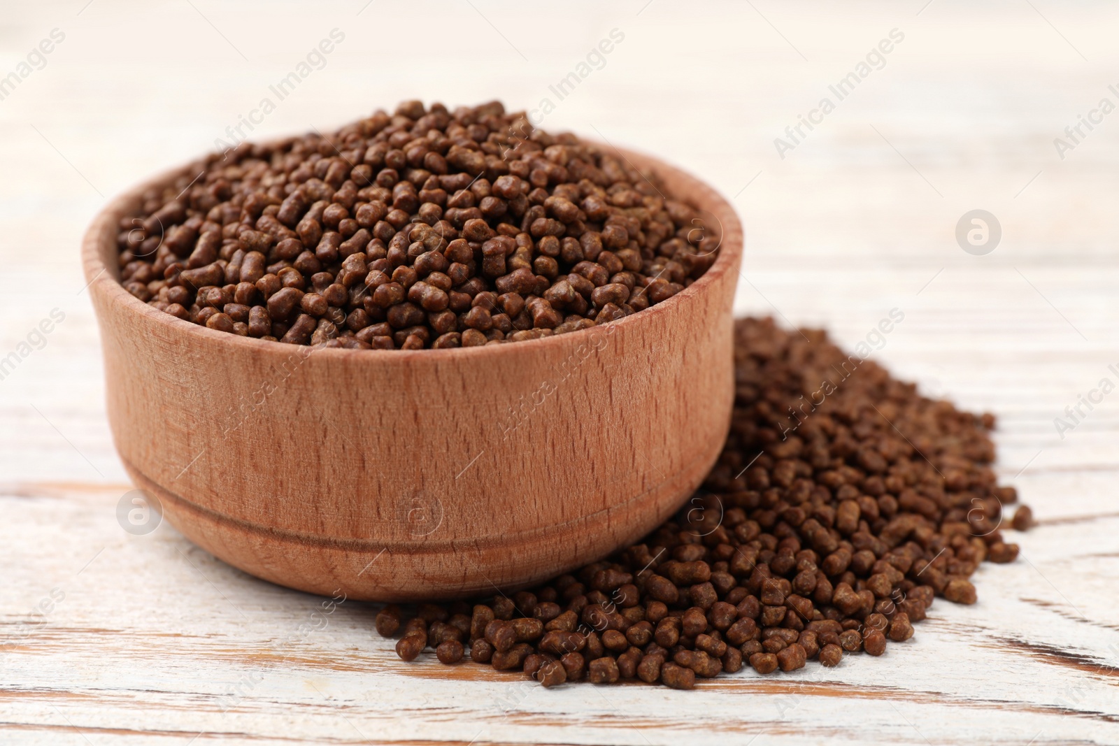 Photo of Bowl with buckwheat tea granules on white wooden table, closeup