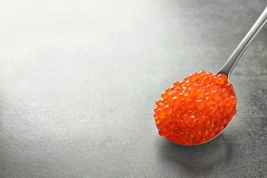 Photo of Spoon with delicious red caviar on grey background