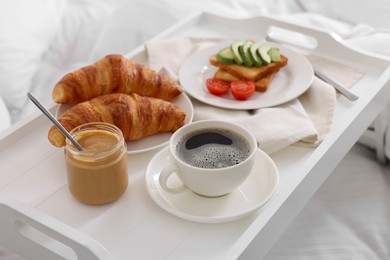 Photo of Good morning. Tray with tasty breakfast on bed, closeup