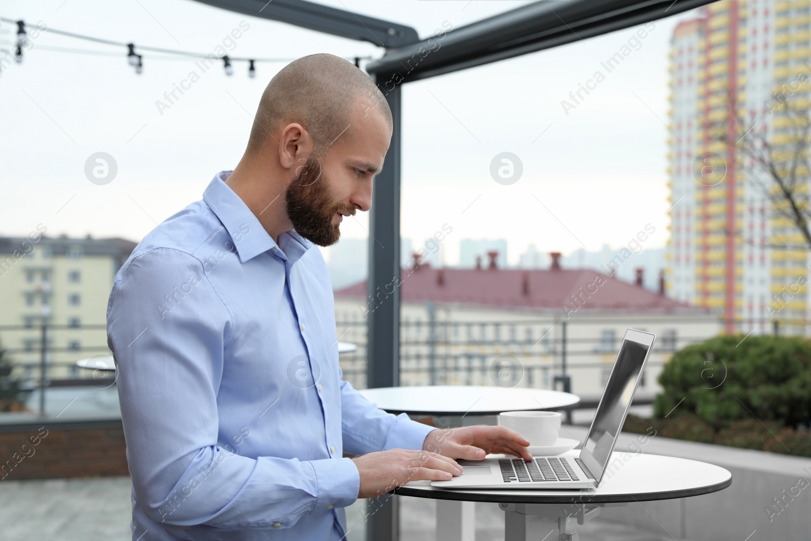 Photo of Businessman working with laptop in outdoor cafe. Corporate blog