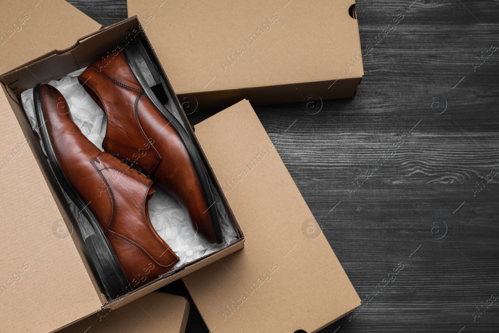 Photo of Stylish men's shoes and cardboard boxes on wooden floor, flat lay. Space for text