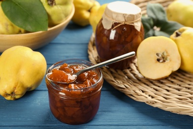Photo of Delicious quince jam and fruits on blue wooden table, closeup