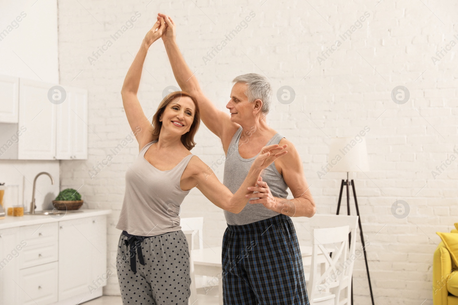 Photo of Happy senior couple dancing together in kitchen