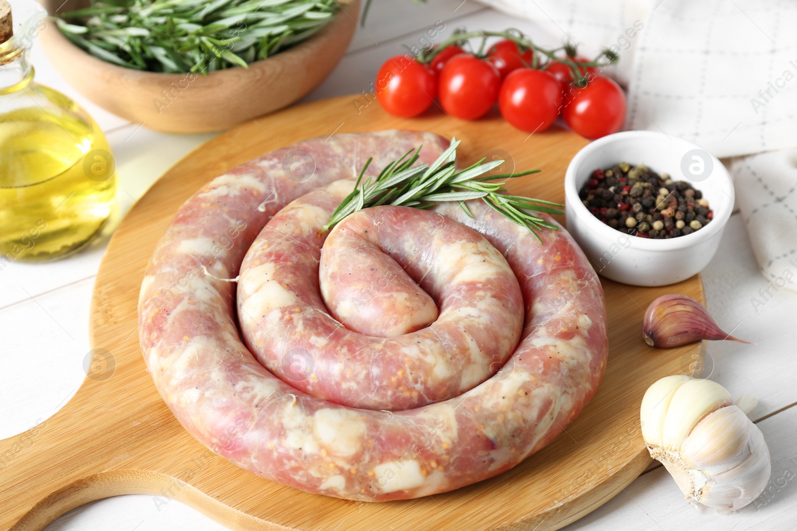 Photo of Raw homemade sausage, spices and other products on white wooden table, closeup