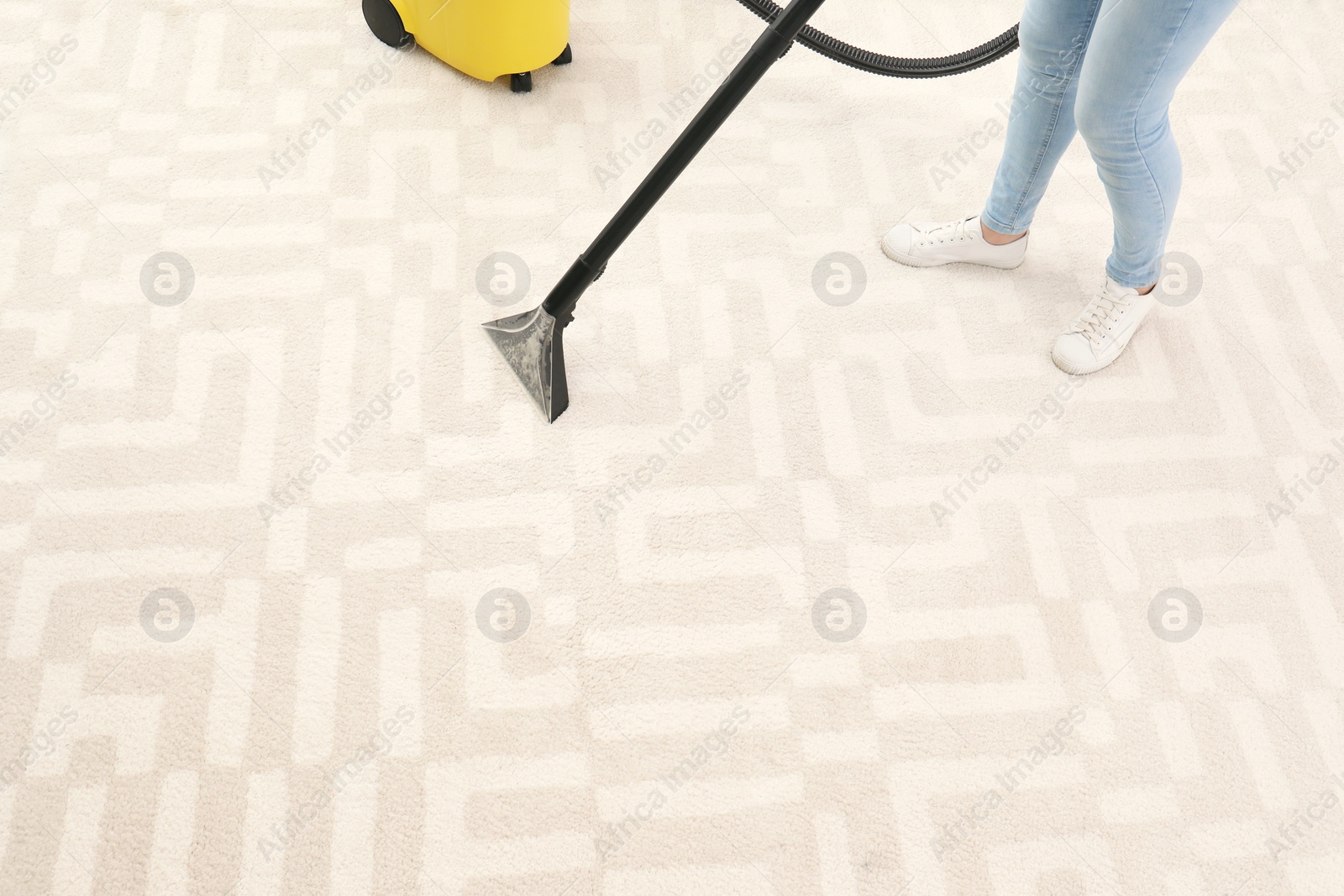 Photo of Woman removing dirt from carpet with vacuum cleaner indoors, closeup. Space for text