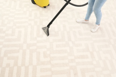 Photo of Woman removing dirt from carpet with vacuum cleaner indoors, closeup. Space for text