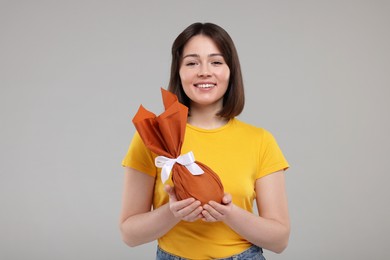 Photo of Easter celebration. Happy woman with wrapped egg on grey background