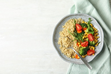 Plate with quinoa and garnish on table, top view. Space for text