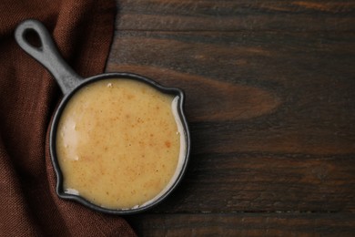 Photo of Delicious turkey gravy in saucepan on wooden table, top view. Space for text