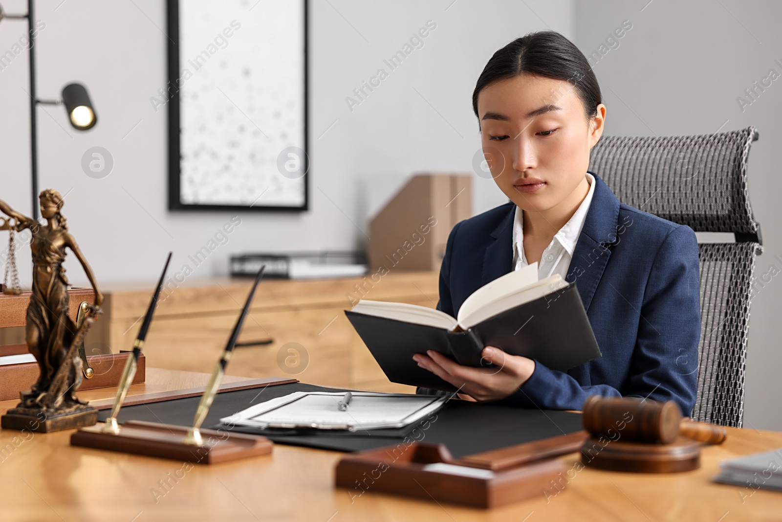 Photo of Notary reading book at table in office