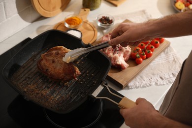 Photo of Man taking cooked tasty meat from frying pan, closeup