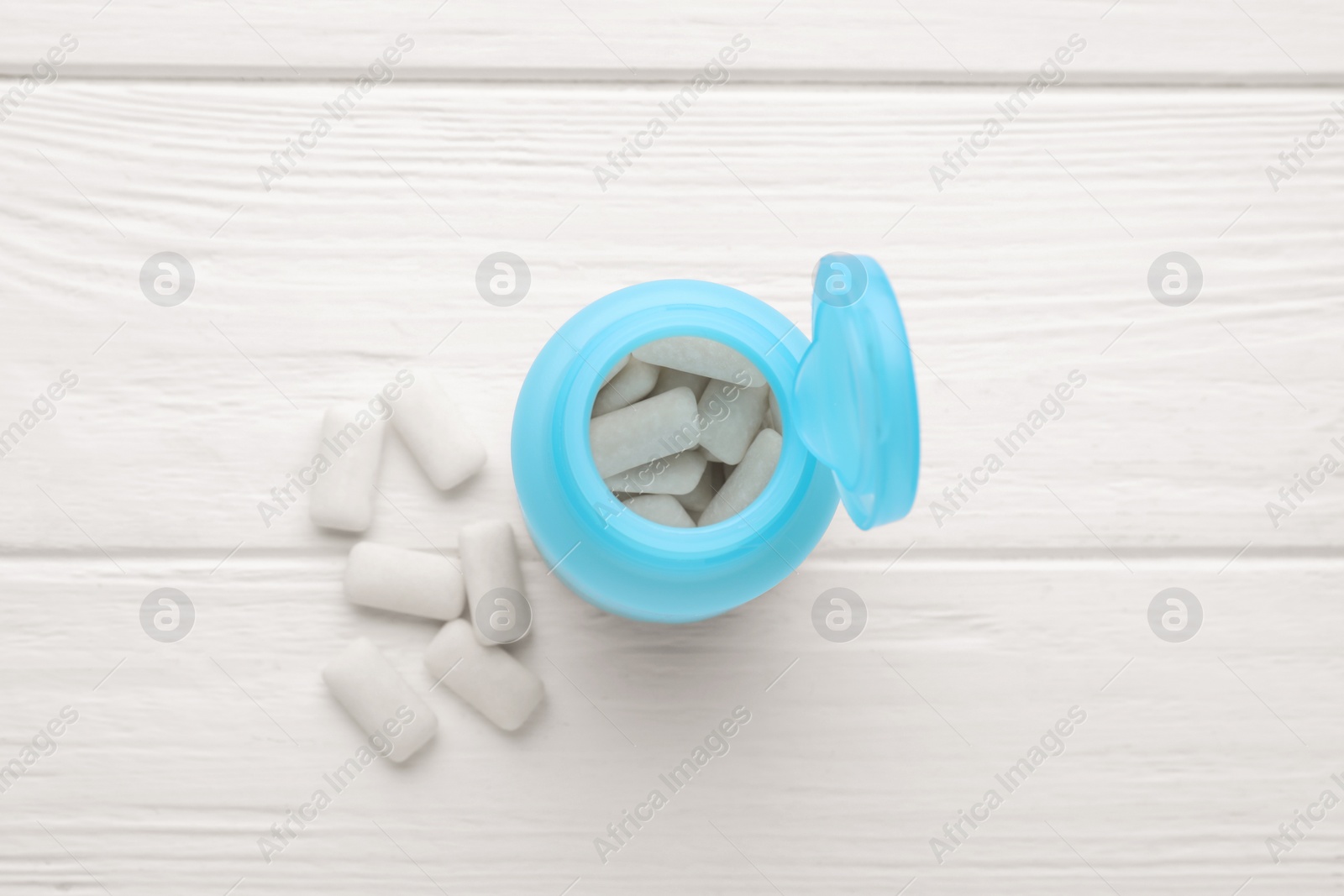 Photo of Jar with chewing gums on white wooden table, flat lay