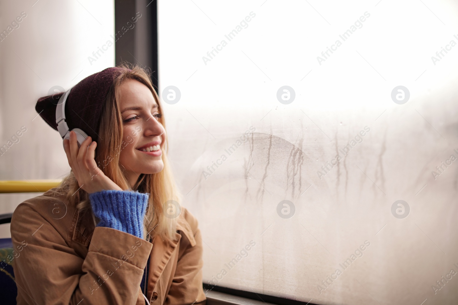 Photo of Young woman with headphones listening to music in public transport, space for text
