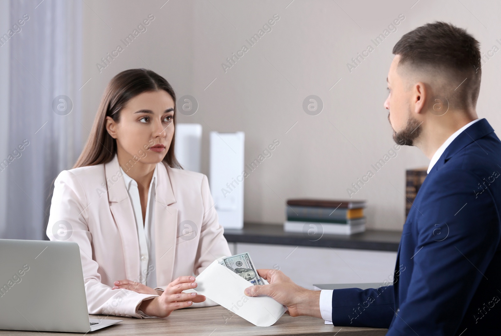 Photo of Man giving bribe to woman at table in office