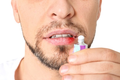 Man applying cream onto lips on white background, closeup