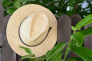 Stylish hat hanging on wooden fence. Beach accessory