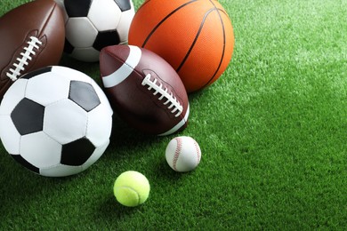 Photo of Set of different sport balls on green grass. Space for text
