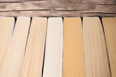 Collection of different books near wooden wall, closeup