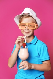 Photo of Little boy with glass of milk shake on color background