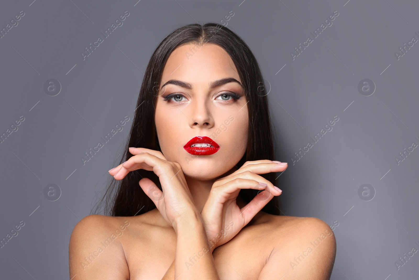 Photo of Portrait of beautiful young woman with red glossy lips on gray background