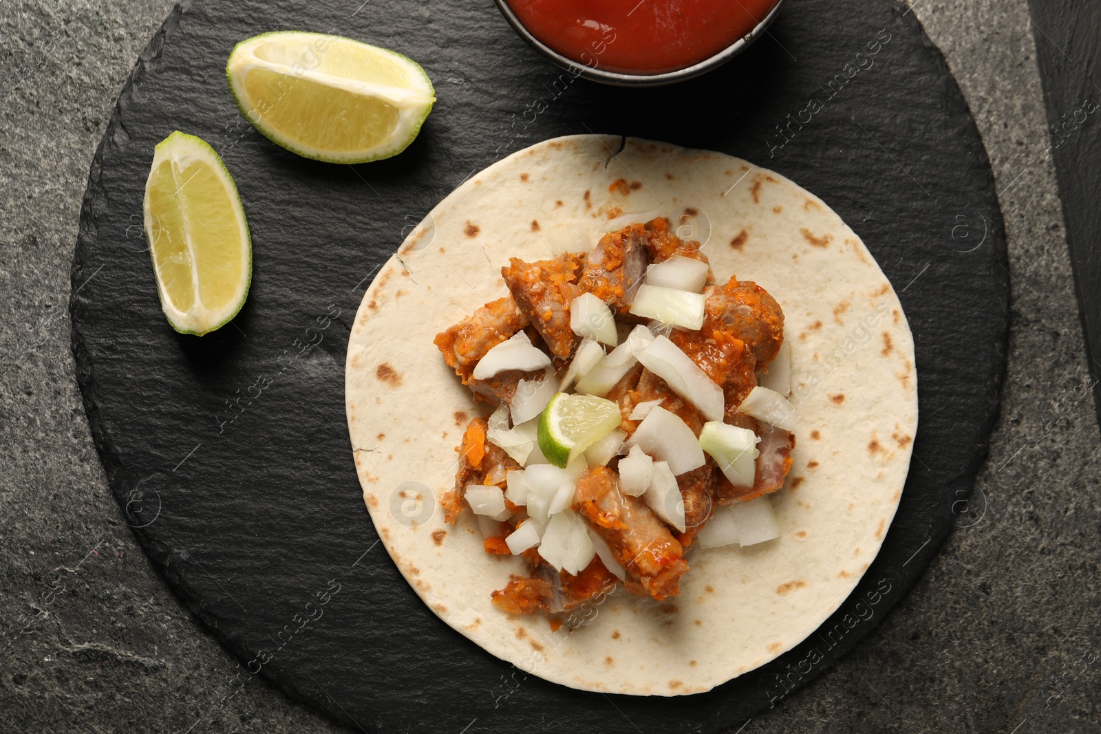 Photo of Delicious taco with vegetables, meat and lime on grey textured table, top view