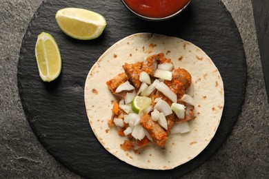 Photo of Delicious taco with vegetables, meat and lime on grey textured table, top view