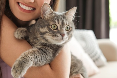 Photo of Young woman with cute cat at home, closeup. Pet and owner