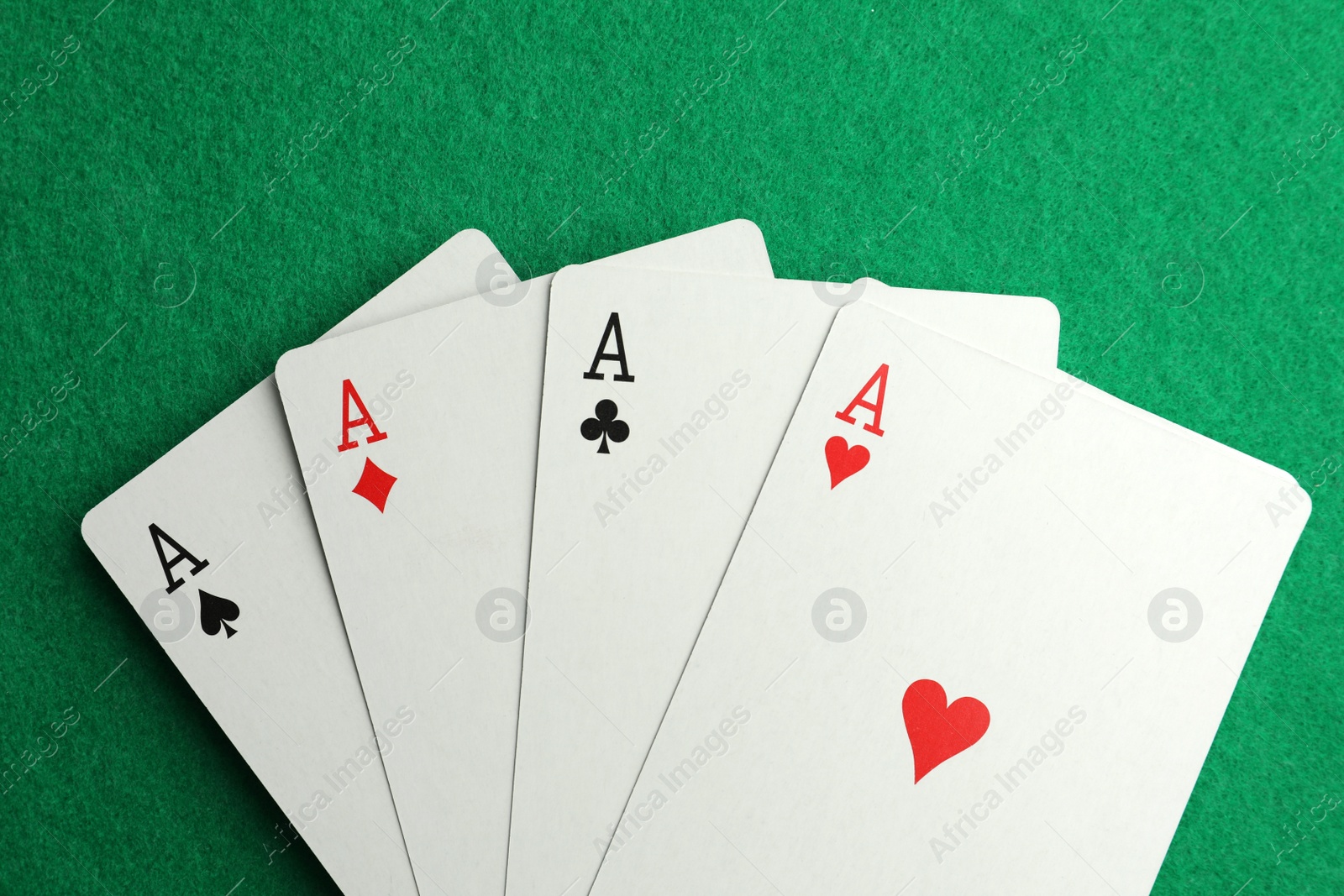 Photo of Four aces playing cards on green table, top view. Poker game