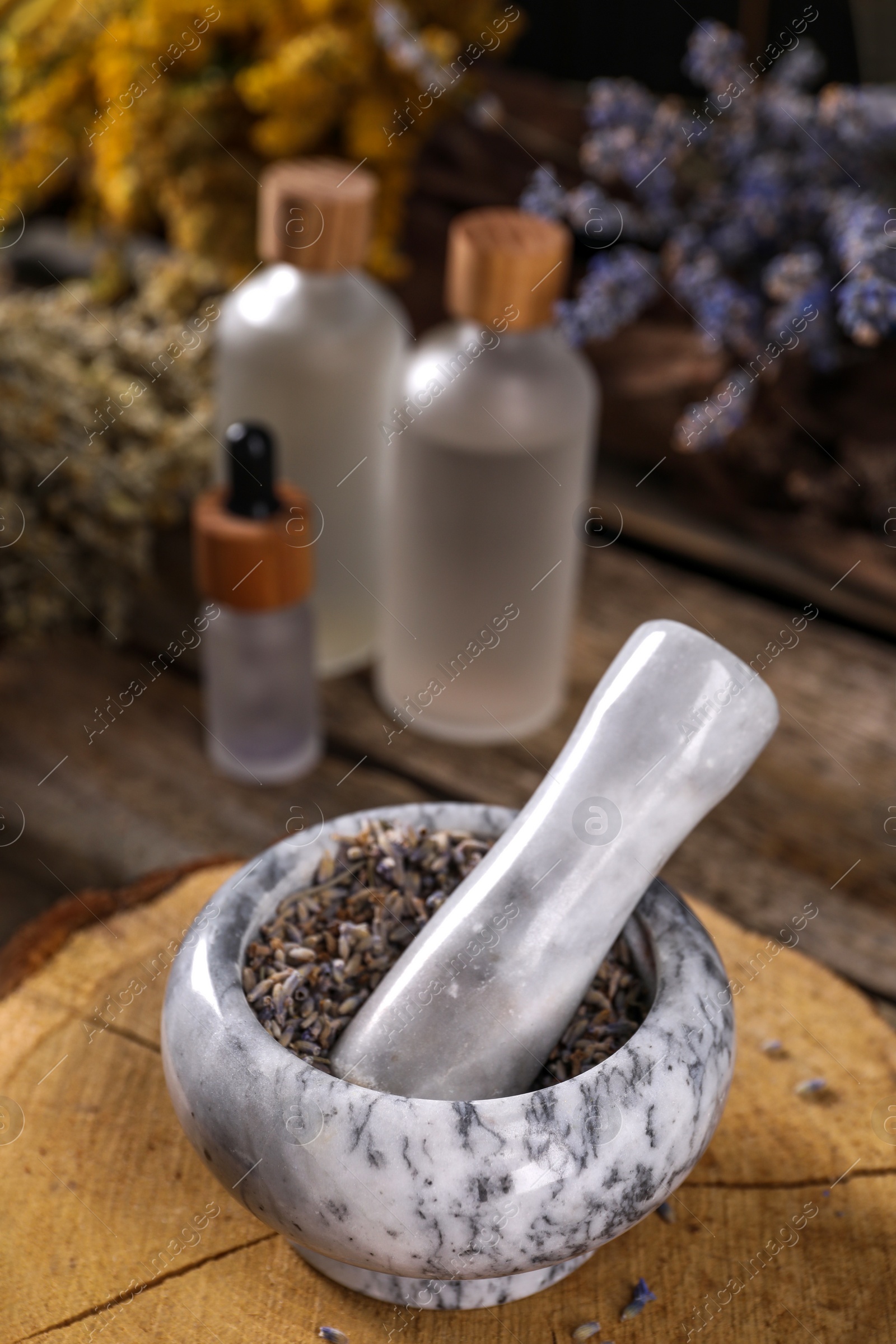 Photo of Mortar with pestle and lavender flowers on wooden table, closeup. Medicinal herbs