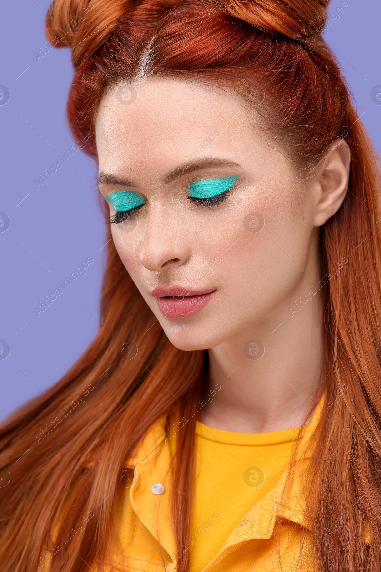 Photo of Beautiful woman with bright makeup and closed eyes on violet background