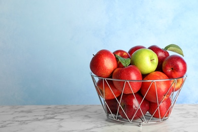 Different apple among red ones in metal basket on table. Space for text