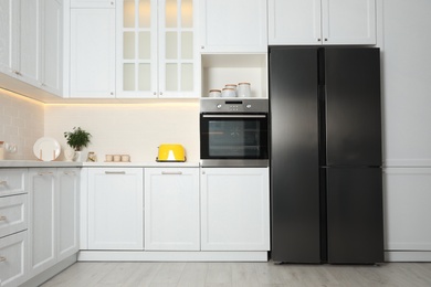 Photo of Stylish kitchen interior with modern steel refrigerator