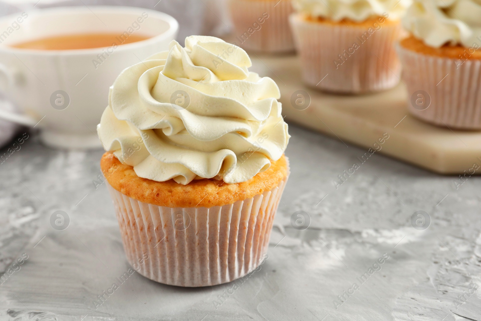 Photo of Tasty cupcakes with vanilla cream on grey table, closeup