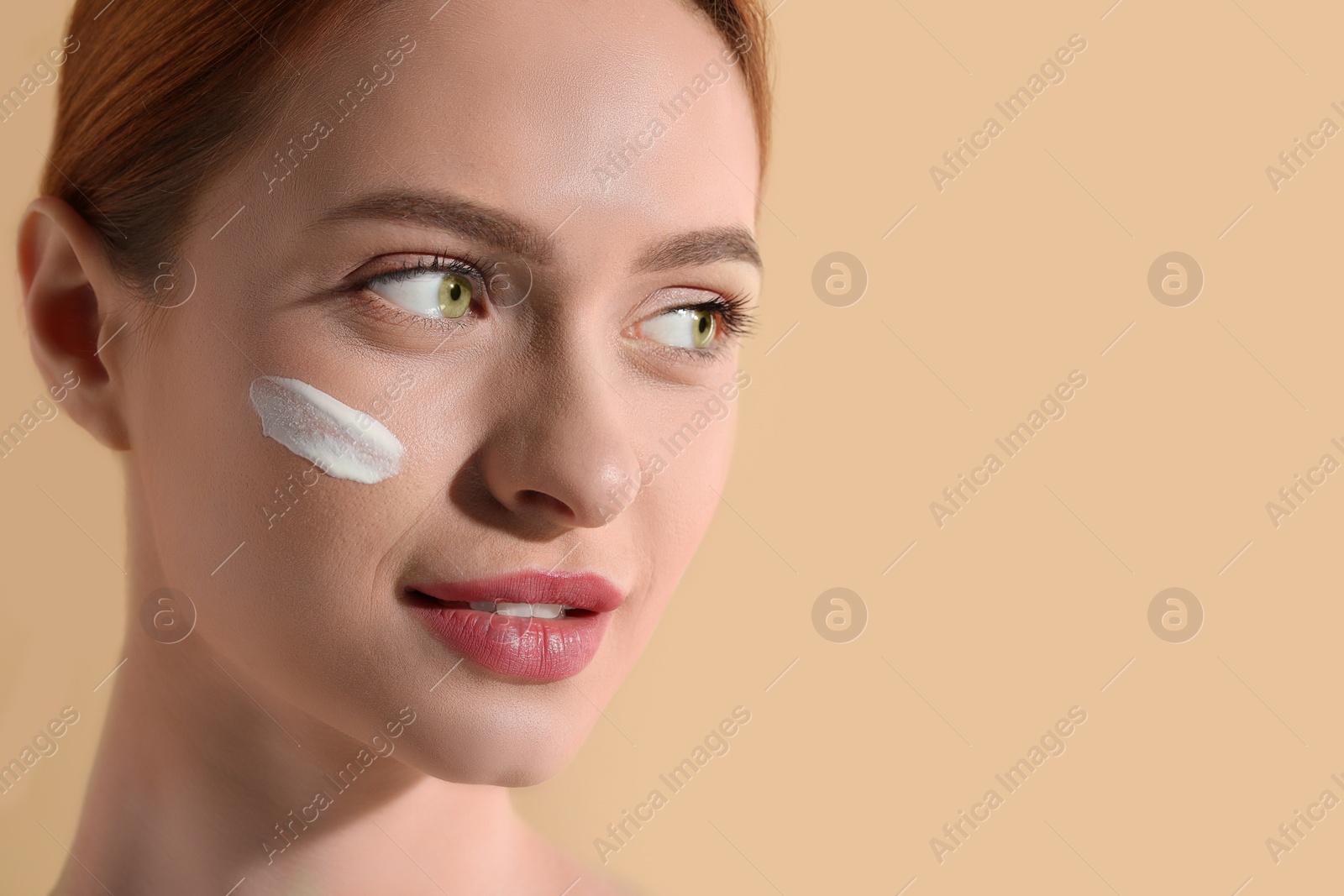 Photo of Beautiful young woman with sun protection cream on her face against beige background, closeup. Space for text
