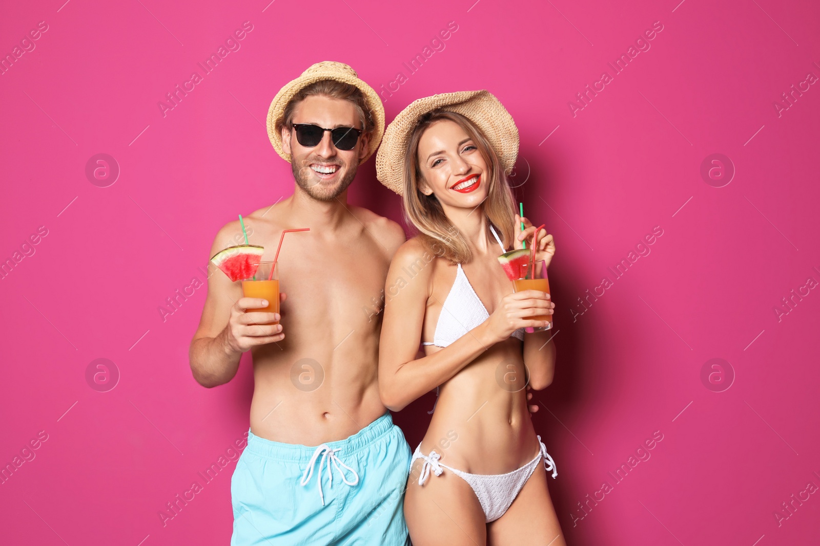 Photo of Happy young couple in beachwear with cocktails on color background