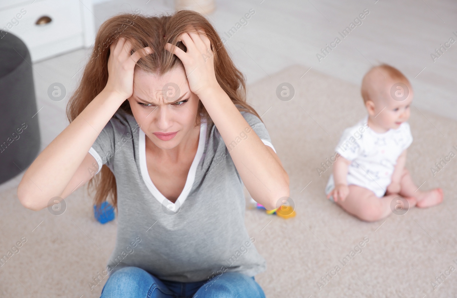 Photo of Young mother suffering from postnatal depression and little baby in room