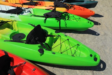 Many colorful kayaks outdoors on sunny day
