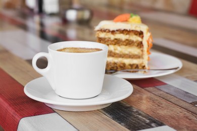 Photo of Cup of hot coffee and delicious cake on wooden table