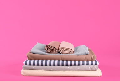 Photo of Stack of clean bed sheets on pink background. Space for text