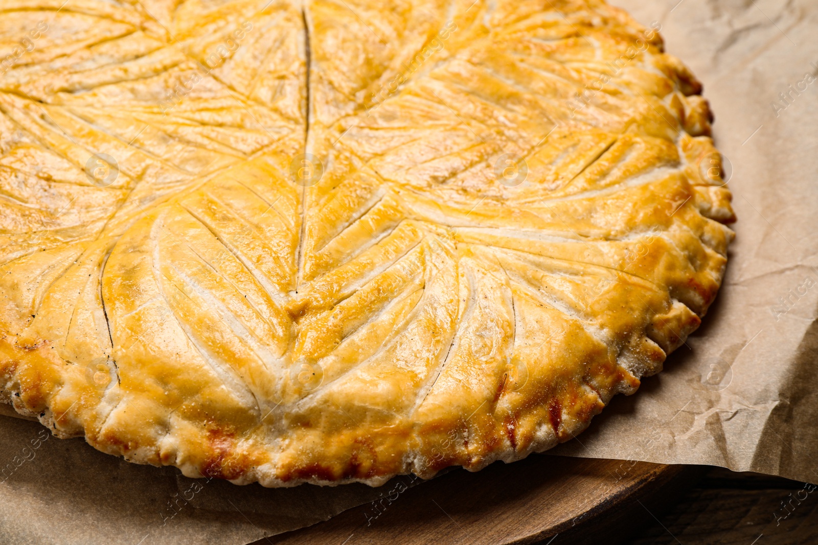 Photo of Traditional galette des rois on wooden board, closeup