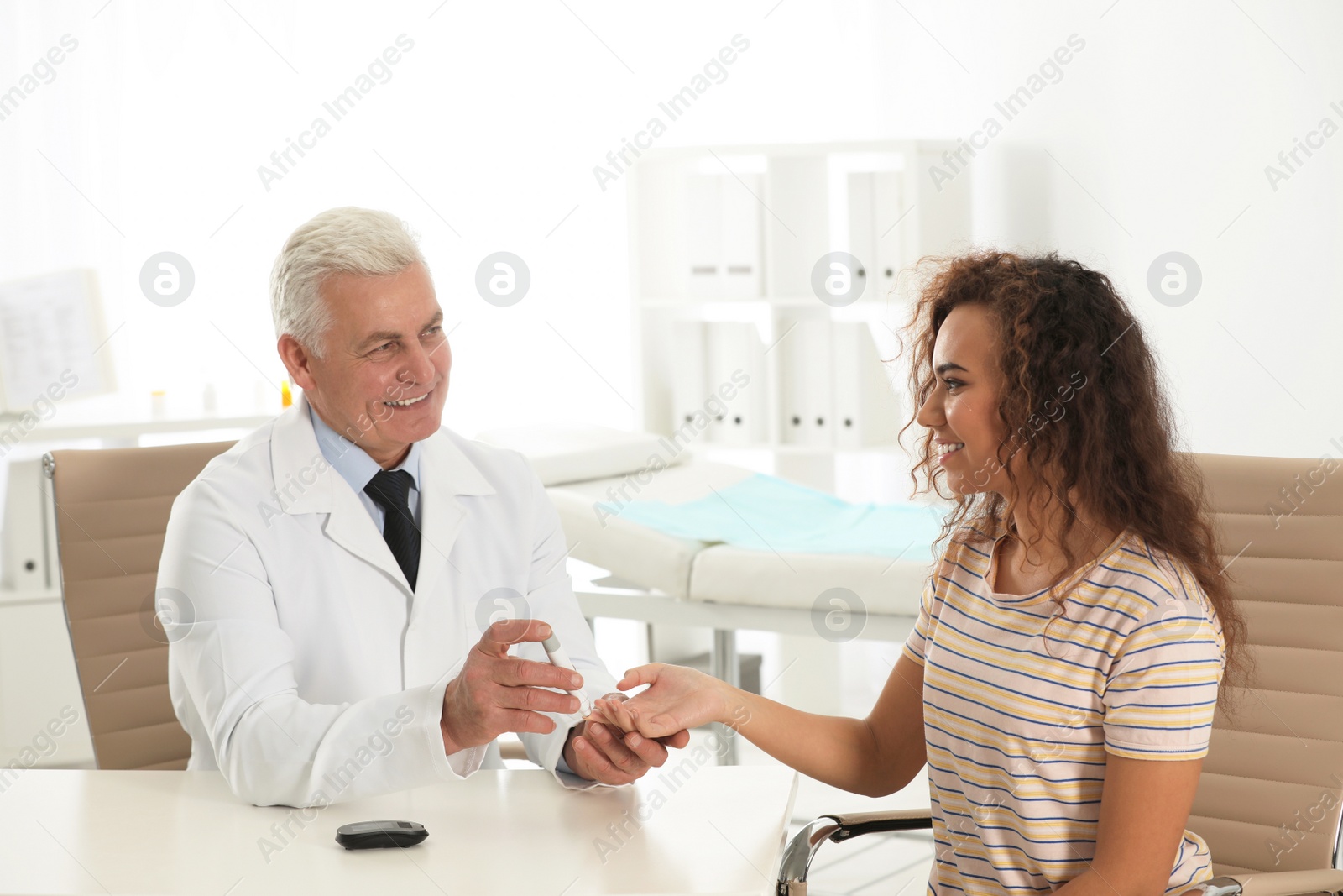 Photo of Doctor taking patient's blood sample with lancet pen in hospital. Diabetes control