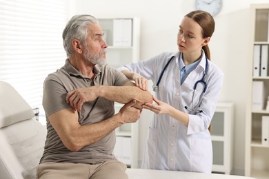 Photo of Arthritis symptoms. Doctor examining patient's elbow in hospital