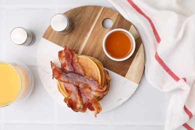 Photo of Delicious pancakes with bacon and glass of juice on white table, flat lay