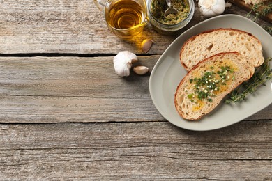 Photo of Tasty bruschettas with oil and garlic on wooden table, flat lay. Space for text