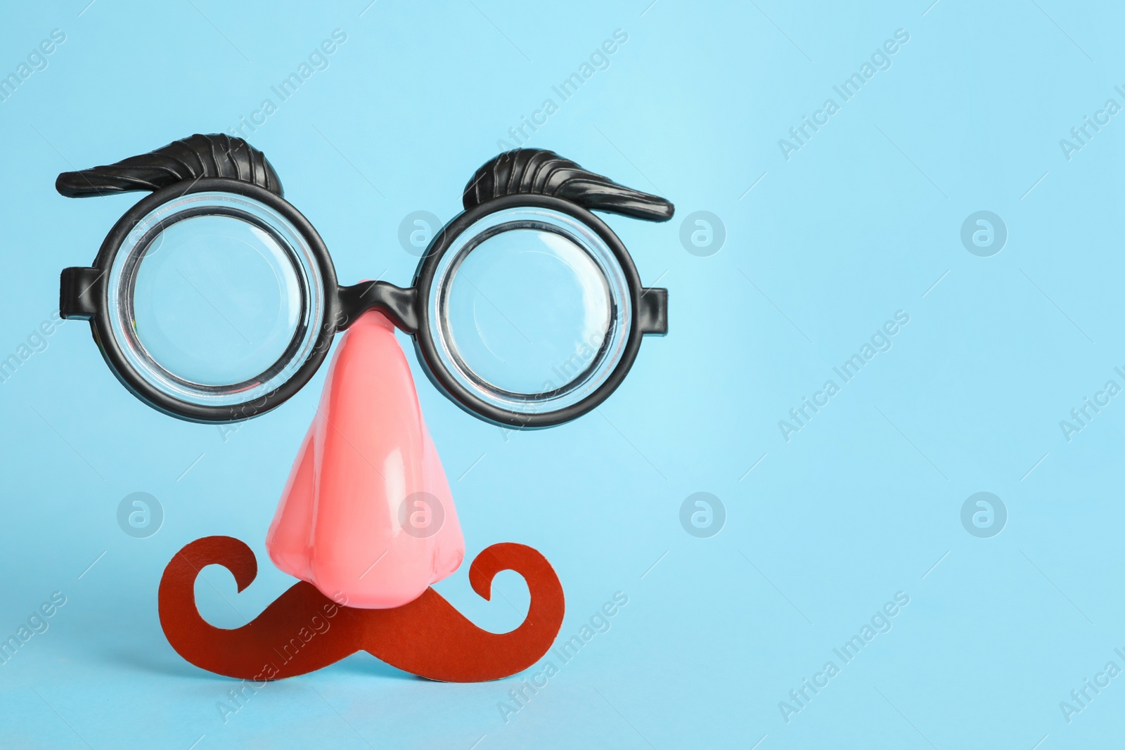 Photo of Funny face made with clown's accessories on light blue background, space for text