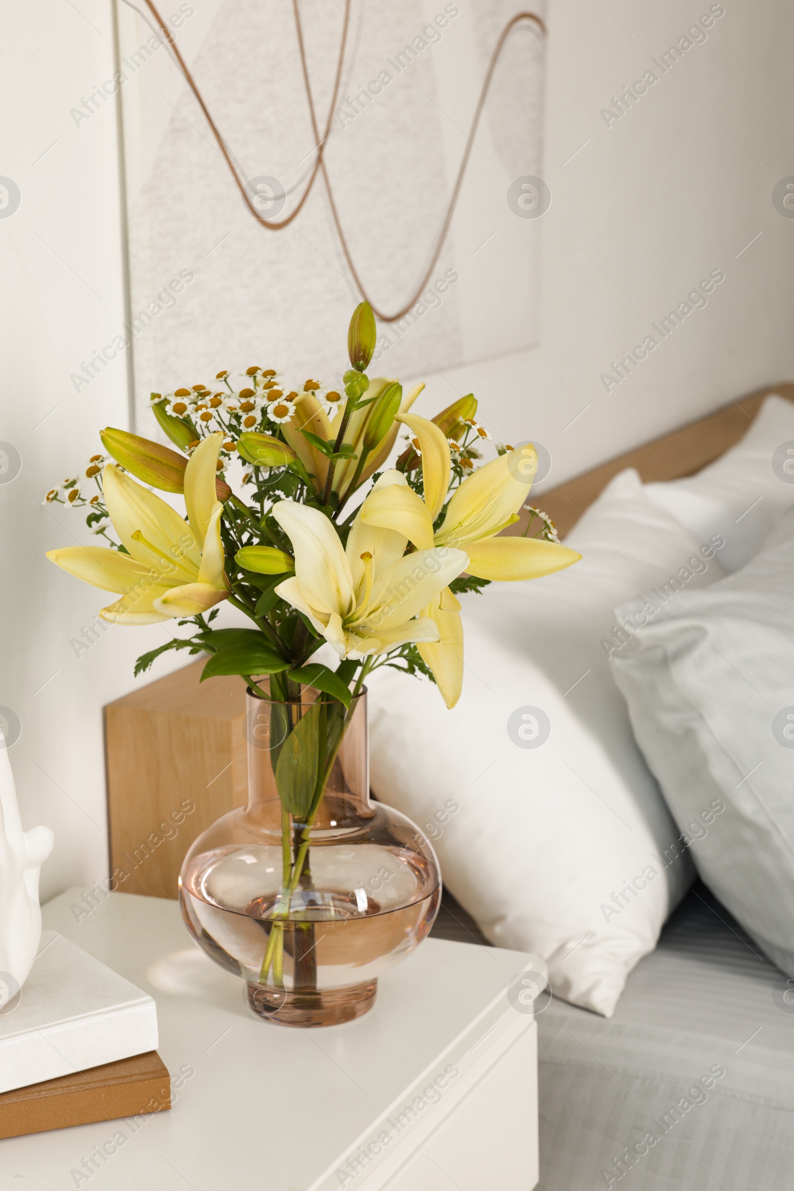 Photo of Vase with bouquet of fresh flowers on white nightstand in bedroom