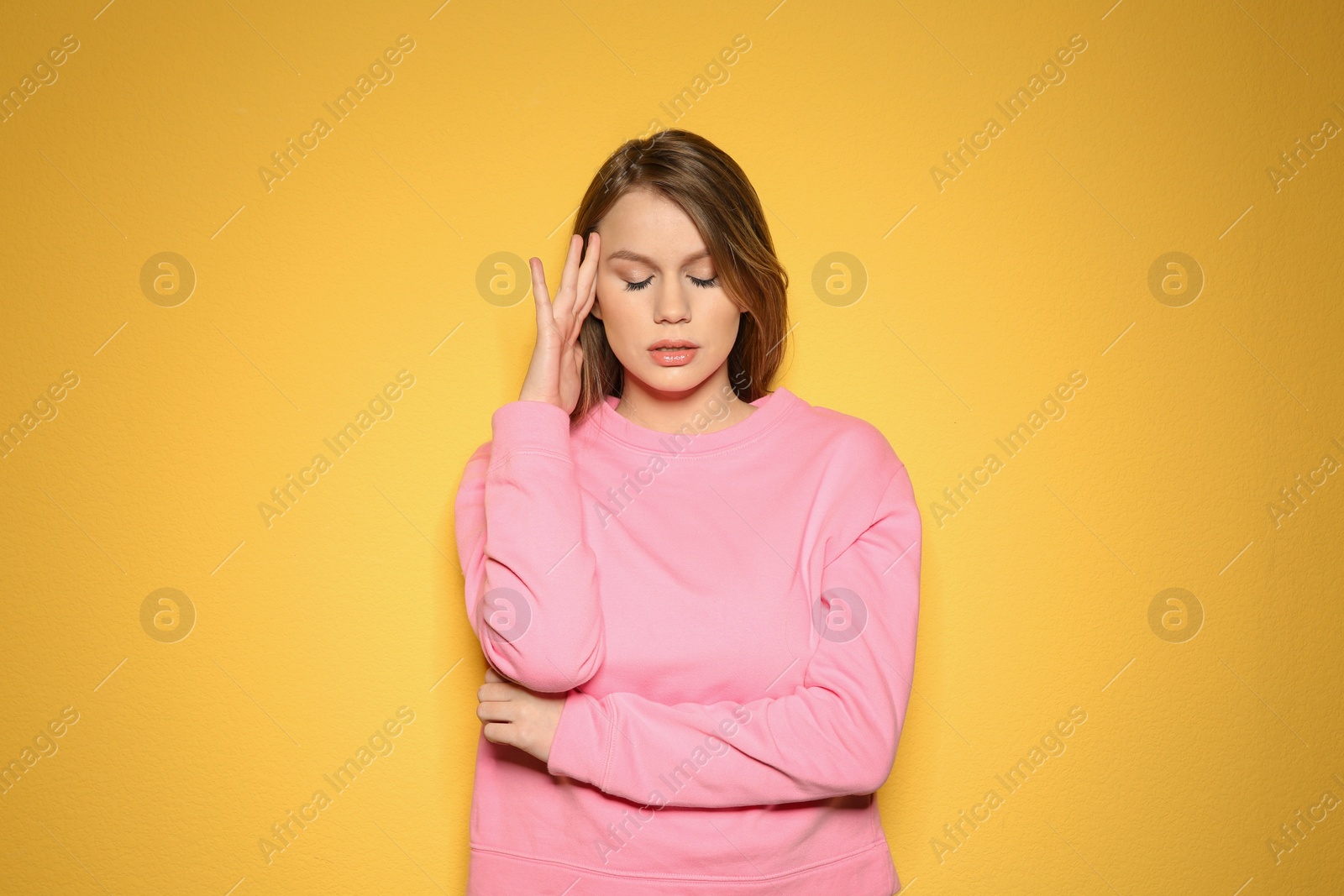 Photo of Young woman suffering from headache on color background