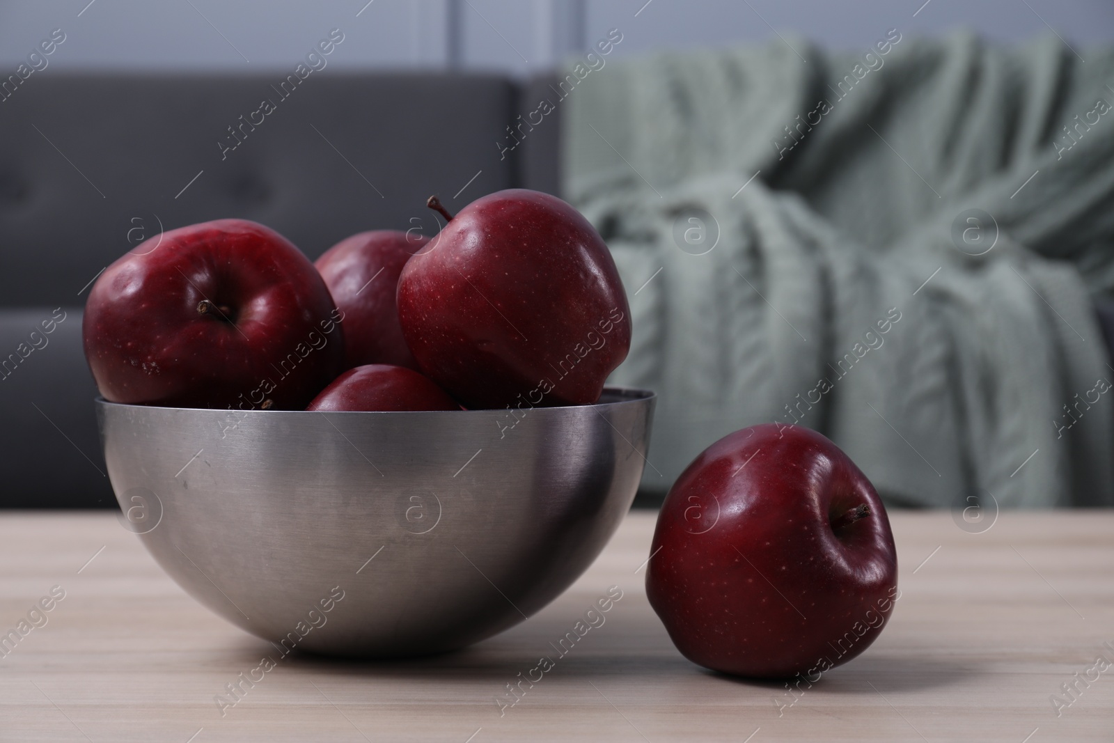 Photo of Red apples in bowl on wooden table indoors