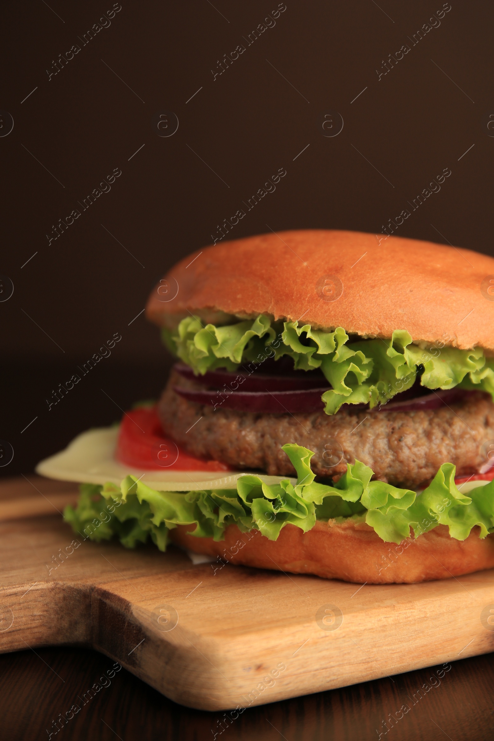 Photo of Tasty burger with vegetables, patty and cheese on wooden table, closeup