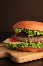 Photo of Tasty burger with vegetables, patty and cheese on wooden table, closeup